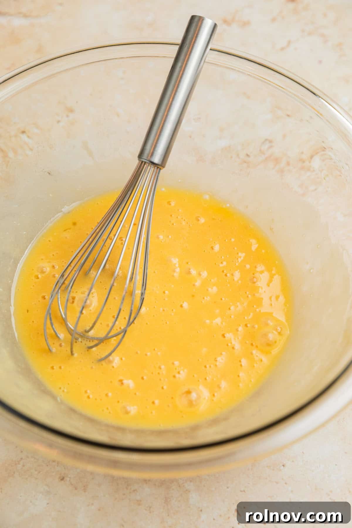Melted butter, egg, and vanilla extract being whisked together in a mixing bowl.