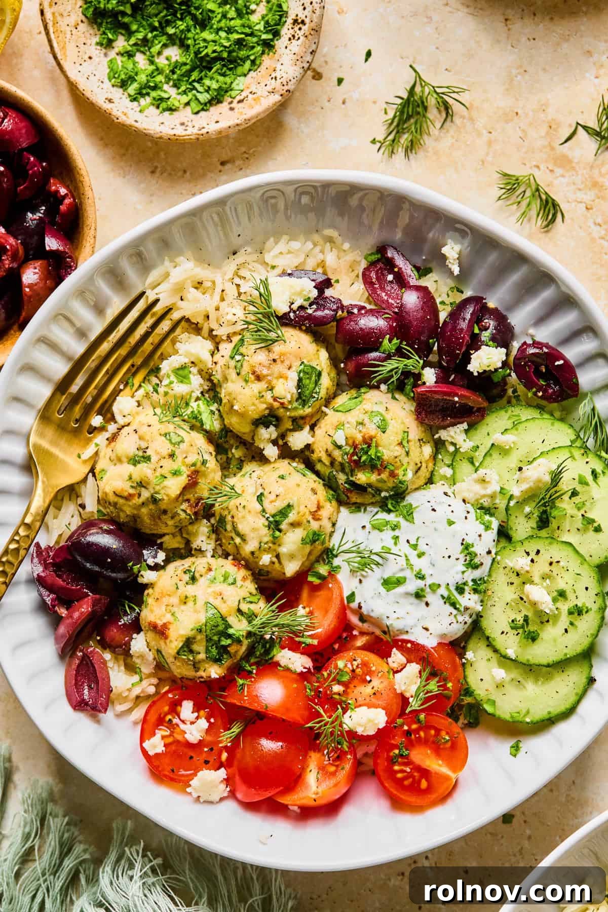 Turkey Meatballs with a Spinach-Feta Swirl 2 Spinach and feta turkey meatballs in bowl with yogurt sauce, cucumbers, olives and more.