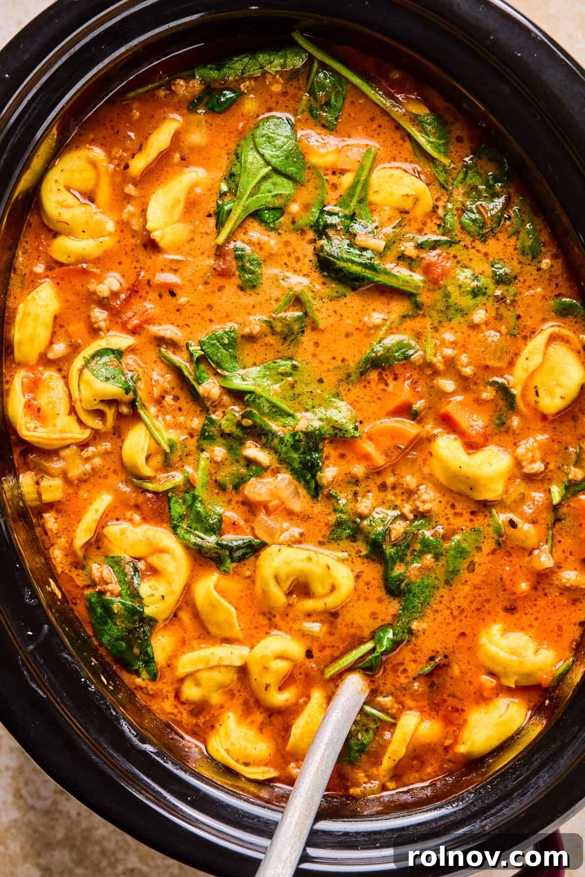 Slow Cooker Creamy Sausage Tortellini Soup 12 The finished Crockpot Sausage Tortellini Soup in the slow cooker, rich and creamy, with a ladle ready to serve.