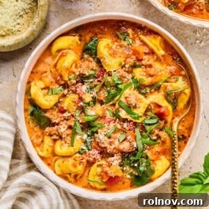Crockpot sausage and tortellini soup in bowl with spoon.