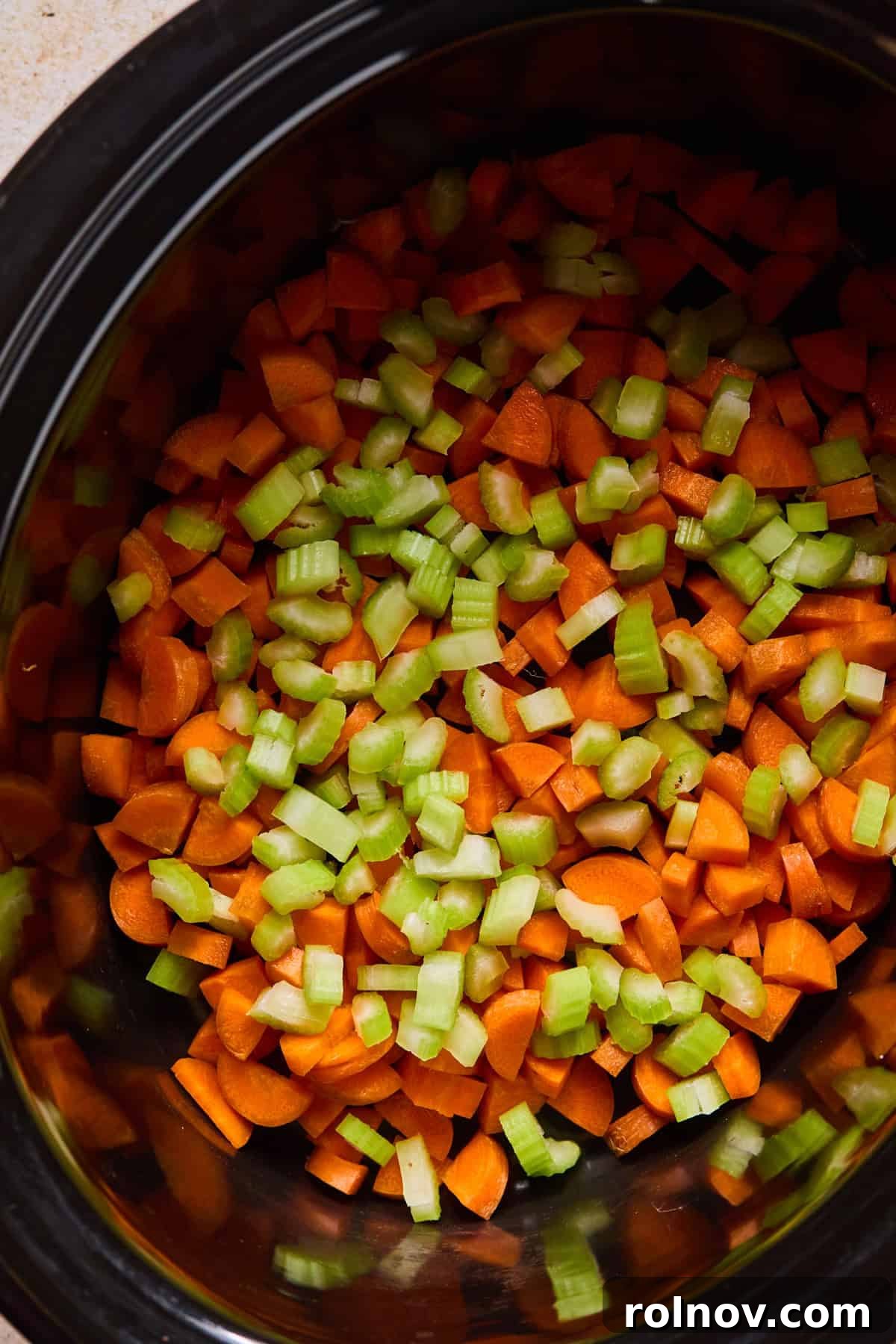 Slow Cooker Creamy Sausage Tortellini Soup 7 Freshly chopped carrots and celery uniformly layered at the bottom of a large crockpot, forming the base for the soup.