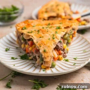 A slice of rich Ground Beef Pot Pie served on a plate, garnished with fresh chopped parsley.