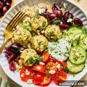 Spinach and feta turkey meatballs artfully arranged on a plate with a fork, garnished with fresh herbs and a drizzle of sauce.