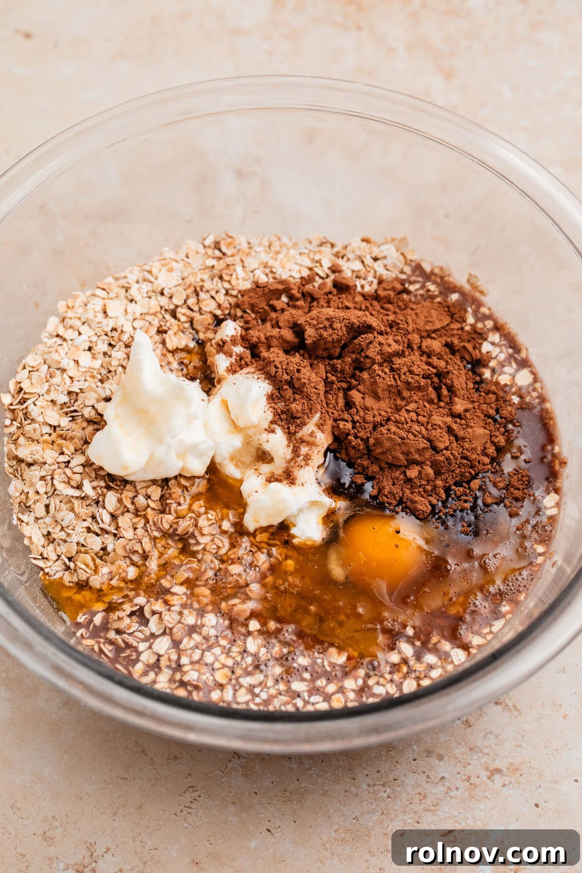 Decadent Chocolate Baked Oats 5 Eggs whisked in a bowl, with quick oats, cocoa powder, butter, and Greek yogurt waiting to be combined.