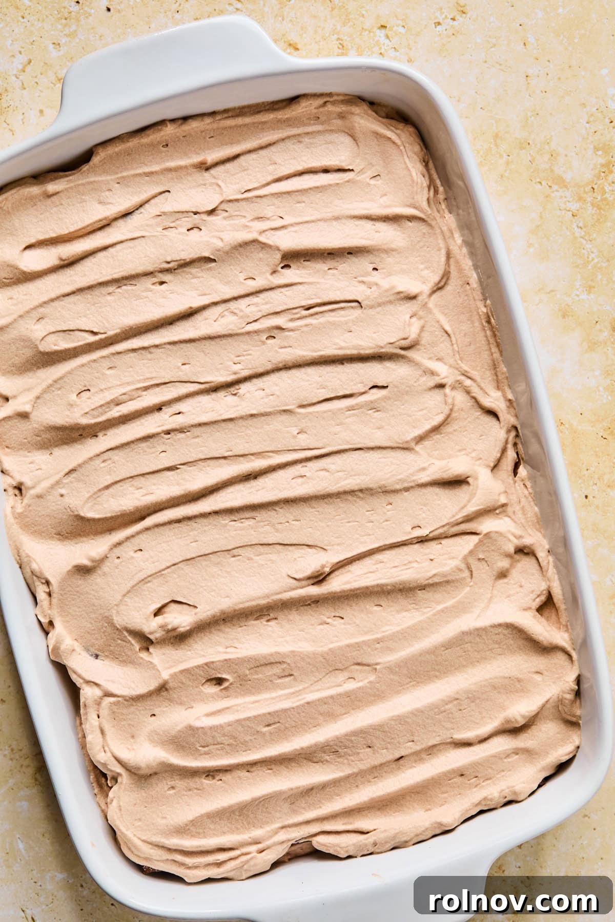 Decadent No-Bake Chocolate Cake 16 The completed hot chocolate icebox cake with a smooth layer of chocolate whipped cream spread evenly over the top, ready for chilling.