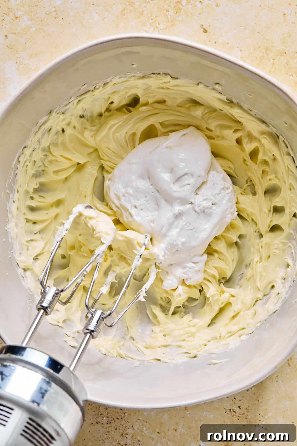 Decadent No-Bake Chocolate Cake 6 Cream cheese, powdered sugar, and vanilla extract being whipped together in a bowl, with marshmallow cream spooned over the top.
