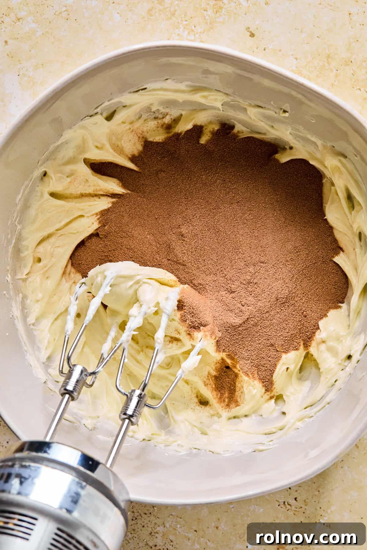 Decadent No-Bake Chocolate Cake 7 Hot cocoa mix being added to the creamy cream cheese mixture in a bowl.