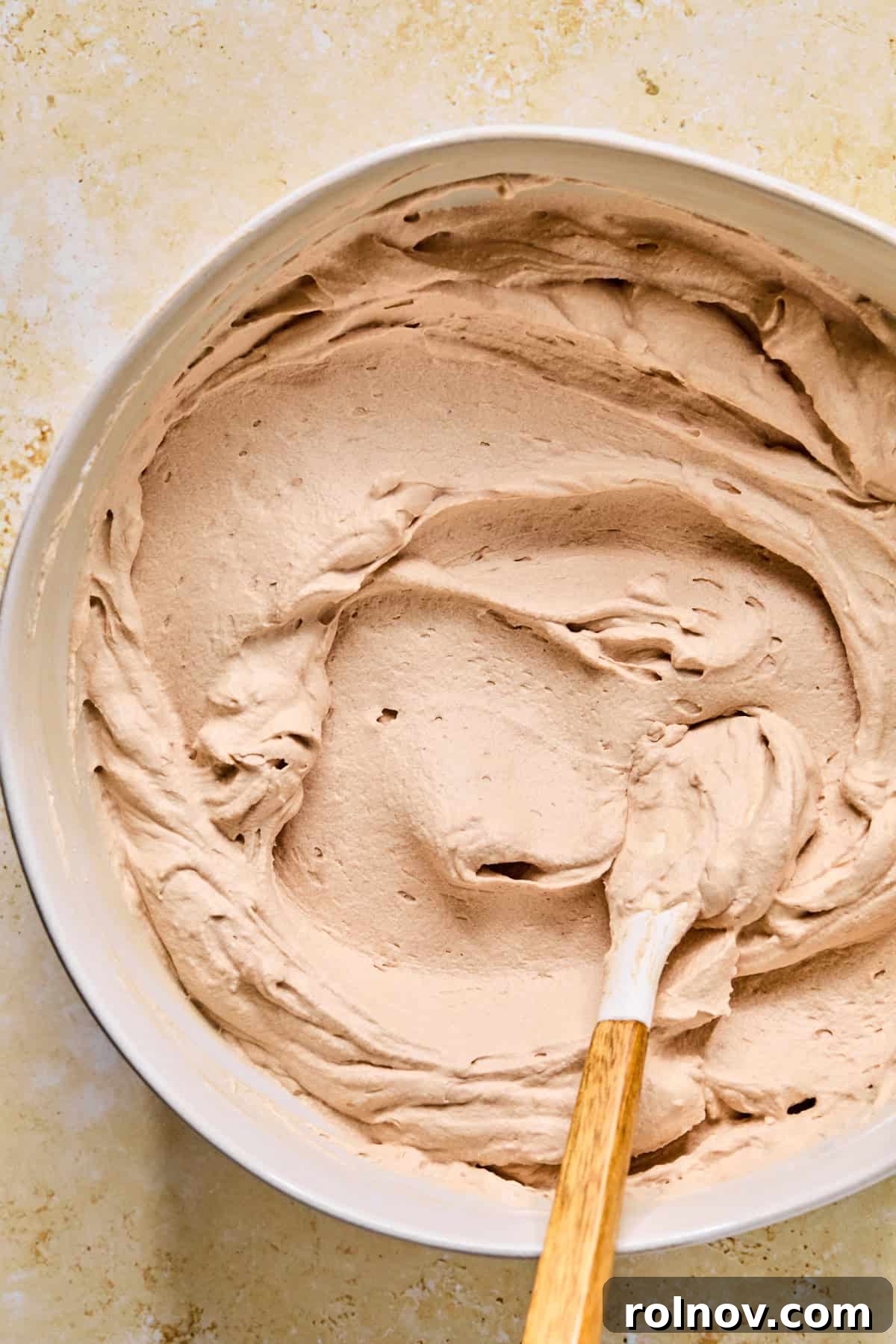 Decadent No-Bake Chocolate Cake 10 The creamy hot cocoa mixture in a bowl with a spatula, showing the final, smooth consistency after folding in whipped cream.