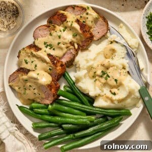 A delectable plate featuring sliced pork tenderloin, elegantly topped with a creamy mustard sauce and garnished with fresh parsley.