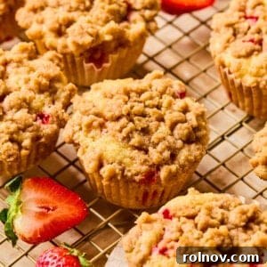 Freshly baked strawberry muffins adorned with a tempting crumble topping, cooling on a wire rack.