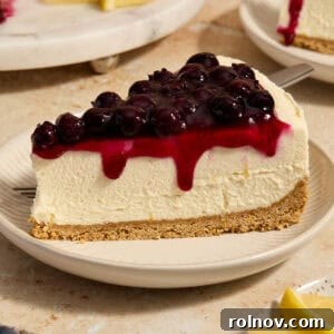 A luscious slice of lemon blueberry cheesecake, served on a pristine white plate, showcasing its vibrant layers.