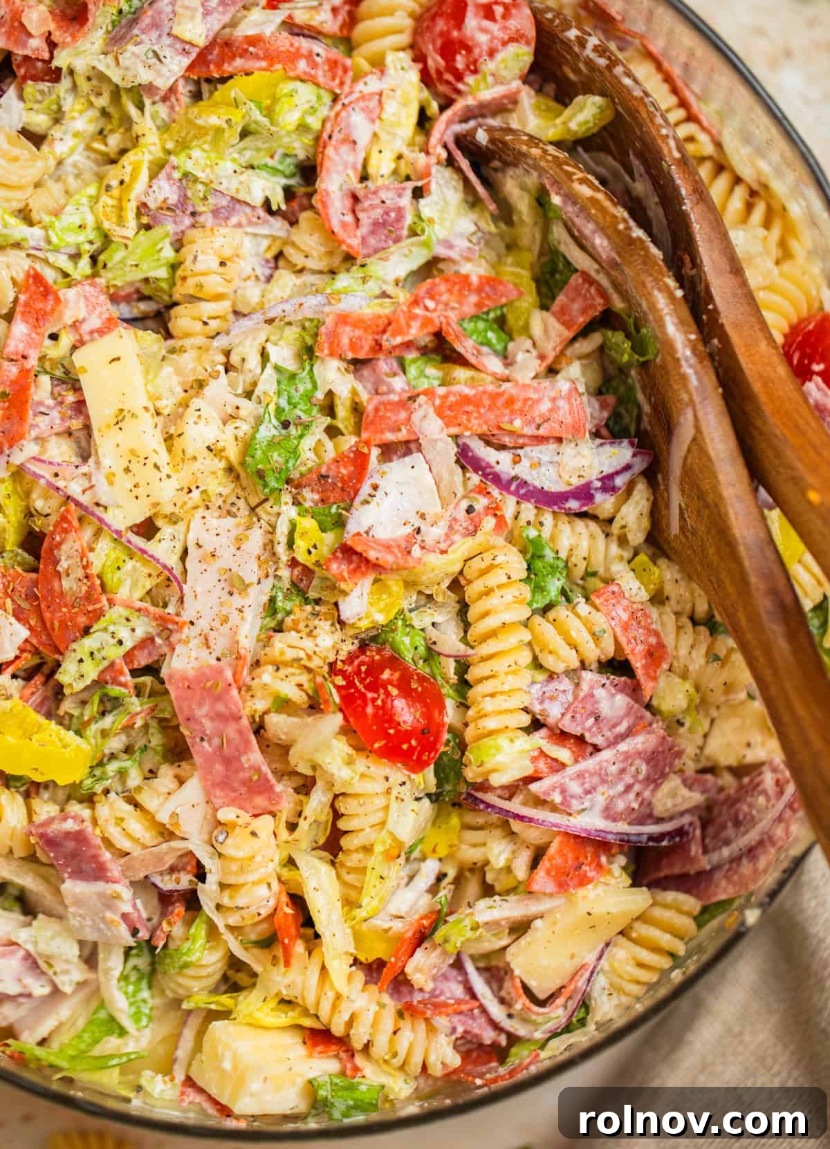 Loaded Grinder Pasta Salad 11 A beautifully presented bowl of Italian Grinder Pasta Salad, garnished and ready for serving, with serving utensils.