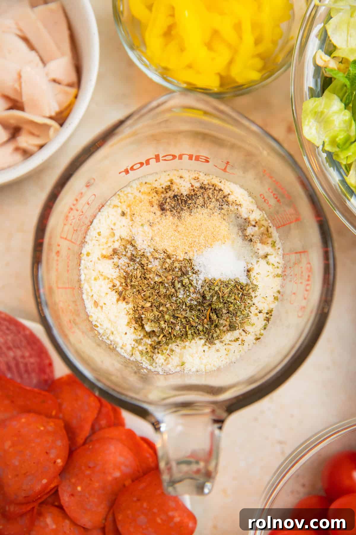 Loaded Grinder Pasta Salad 7 Ingredients for the creamy parmesan dressing: mayonnaise, red wine vinegar, grated parmesan, and various seasonings in a measuring cup.