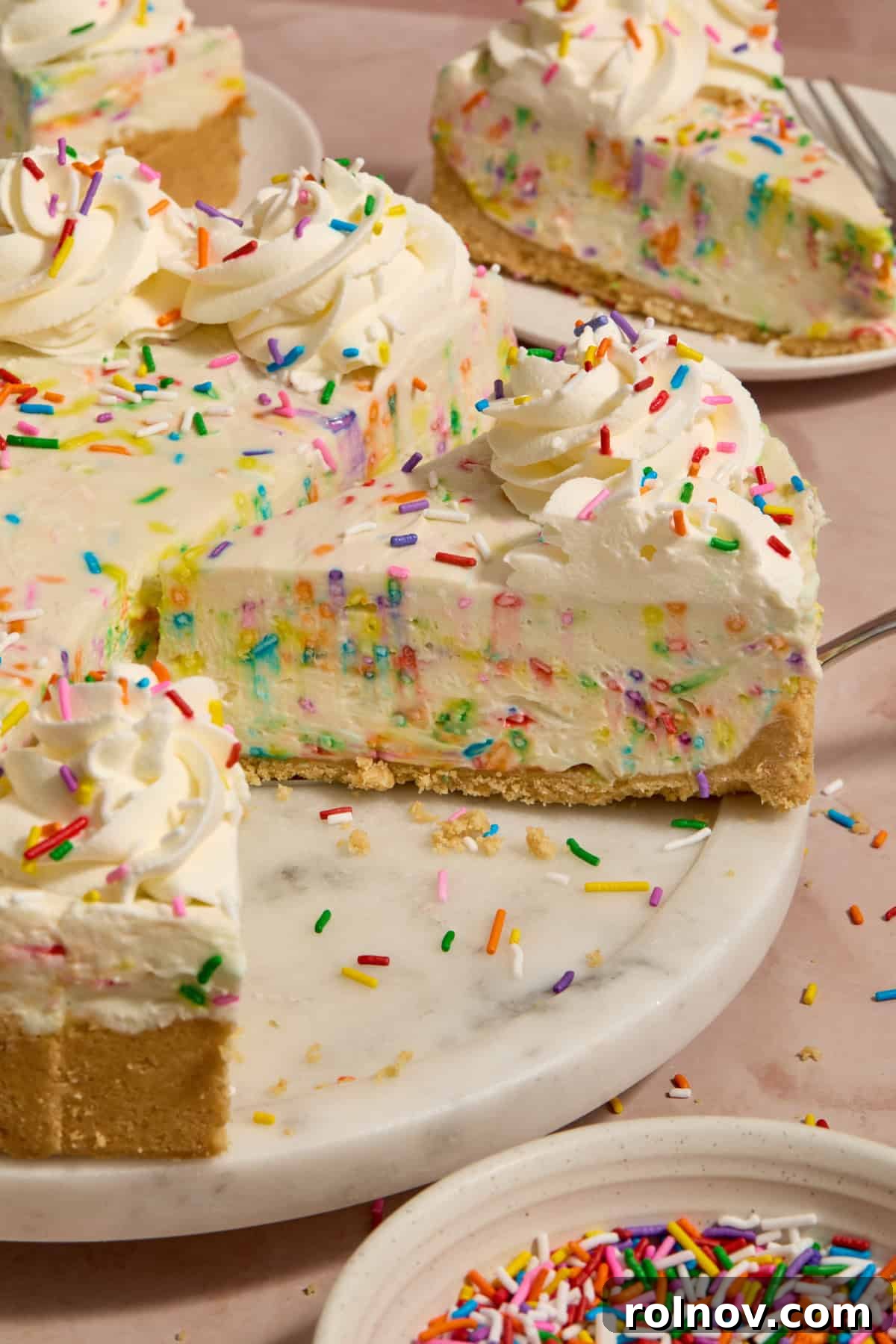 A slice of no-bake funfetti cheesecake on a spatula, ready to be served from the pan.