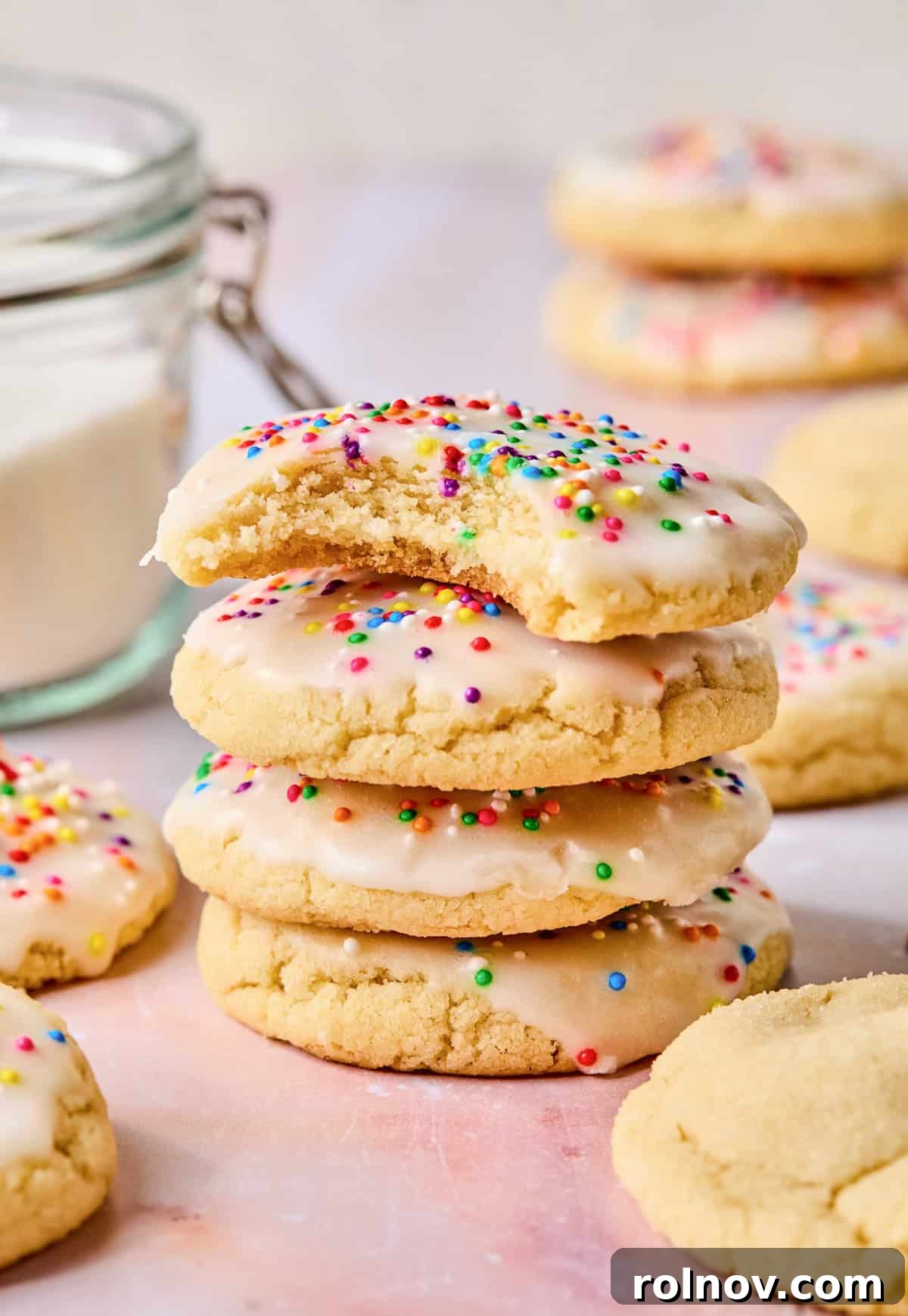 Frosted Sugar Delights 13 A stack of iced sugar cookies, with a bite taken from the top cookie, showcasing the chewy interior.