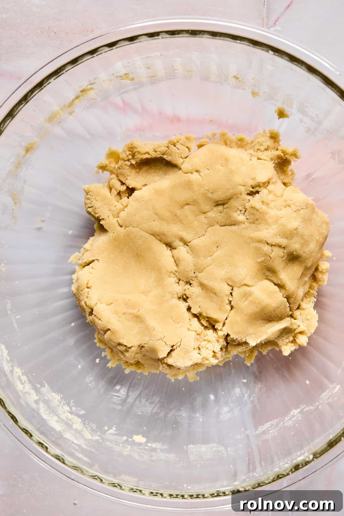 Frosted Sugar Delights 9 Sugar cookie dough resting in a glass mixing bowl, slightly crumbly.