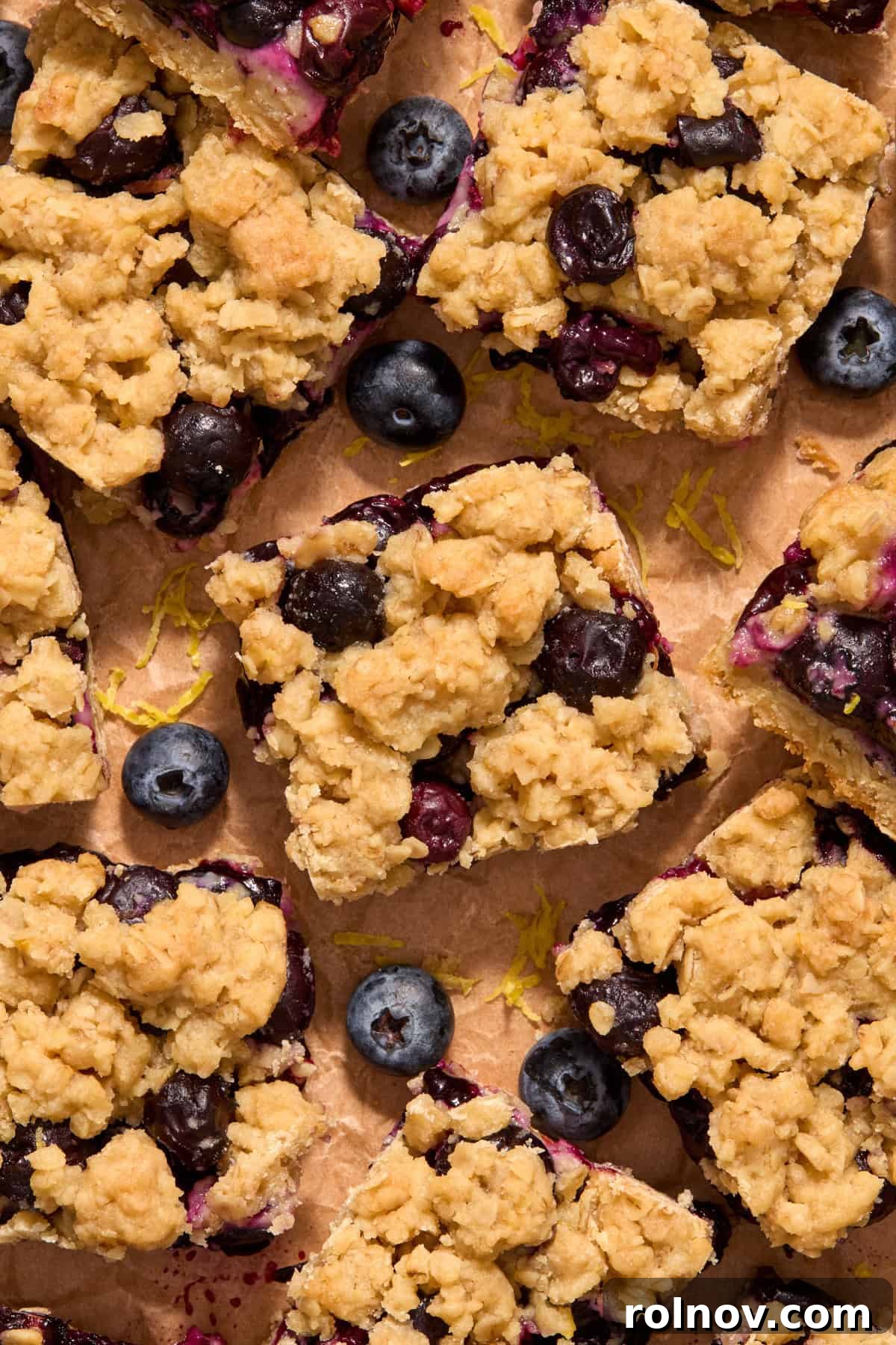 Bright Blueberry Lemon Squares 13 A close-up of baked lemon blueberry oat bars arranged on parchment paper, ready to be served.