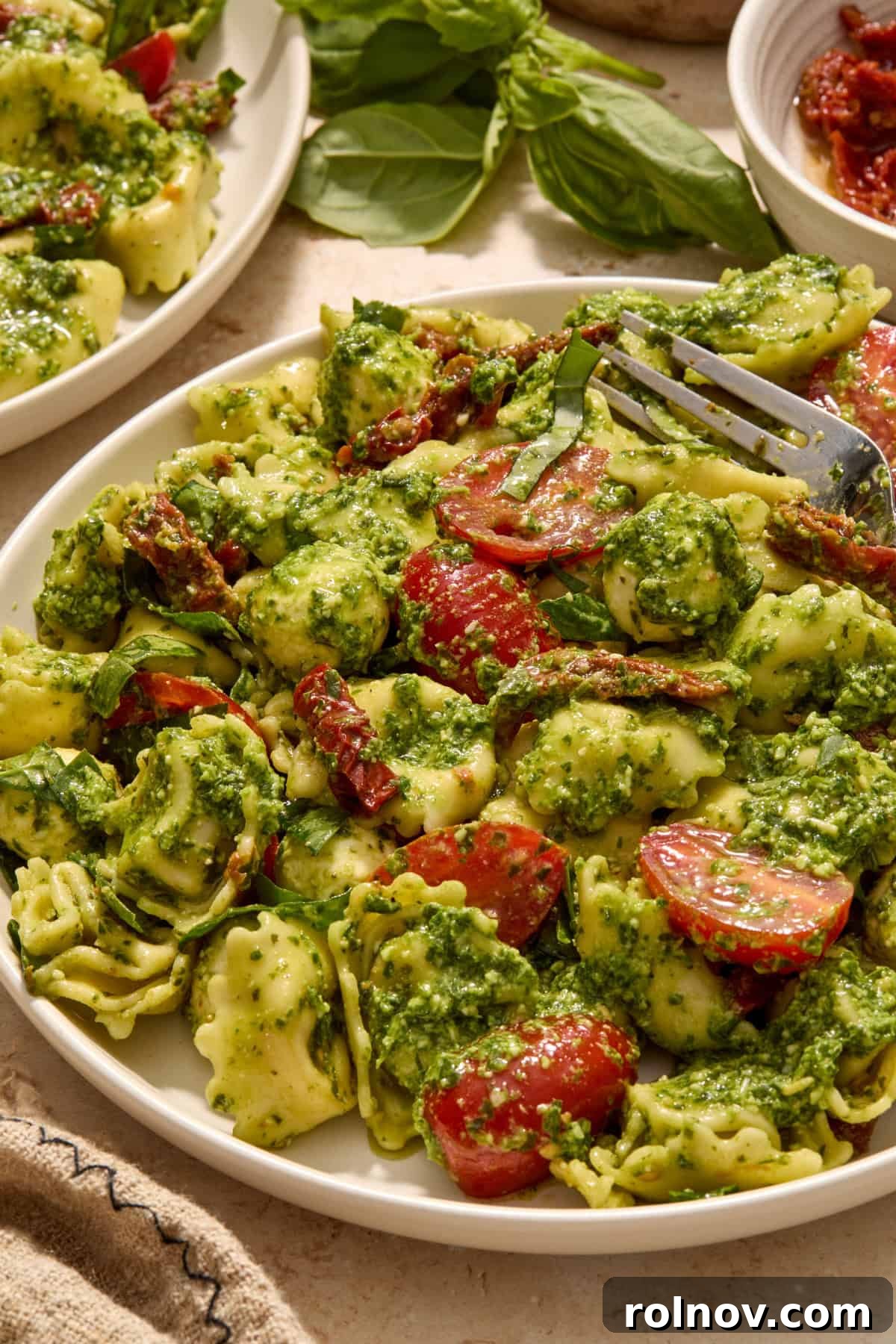 Plate with tortellini pesto salad and fork propped on plate.