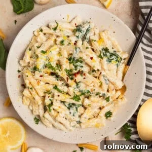 Plate with creamy pasta topped with chopped parsley and lemon zest.