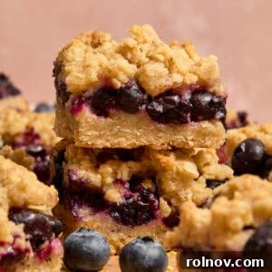 Stacked blueberry lemon bars with blueberries and other bars around it.