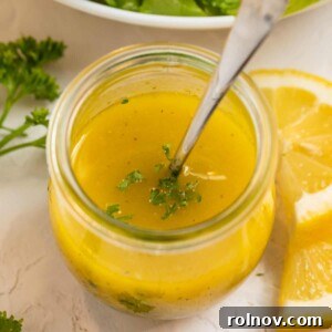 Lemon dijon dressing in glass jar with spoon.