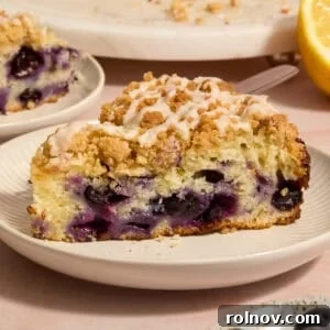 Slice of blueberry lemon coffee cake on plate with icing drizzle on top.