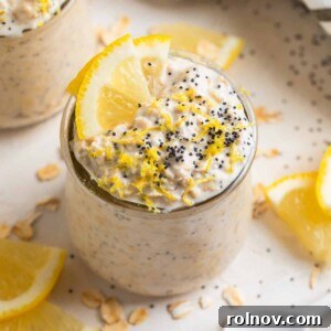 Lemon poppy seed overnight oatmeal in glass jar with lemon slices and poppy seeds on top for garnish.