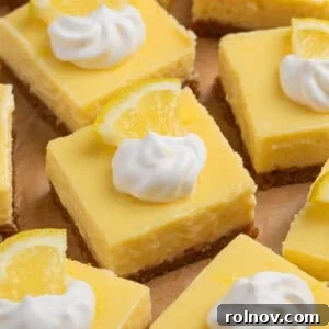 Sliced creamy lemon bars topped with dollop of whipped cream and lemon slice.