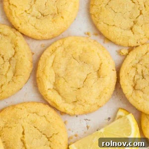 Lemon sugar cookies on surface with lemon wedges.