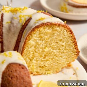 Lemon bundt cake on cake plate with slice cut out to show texture of cake.