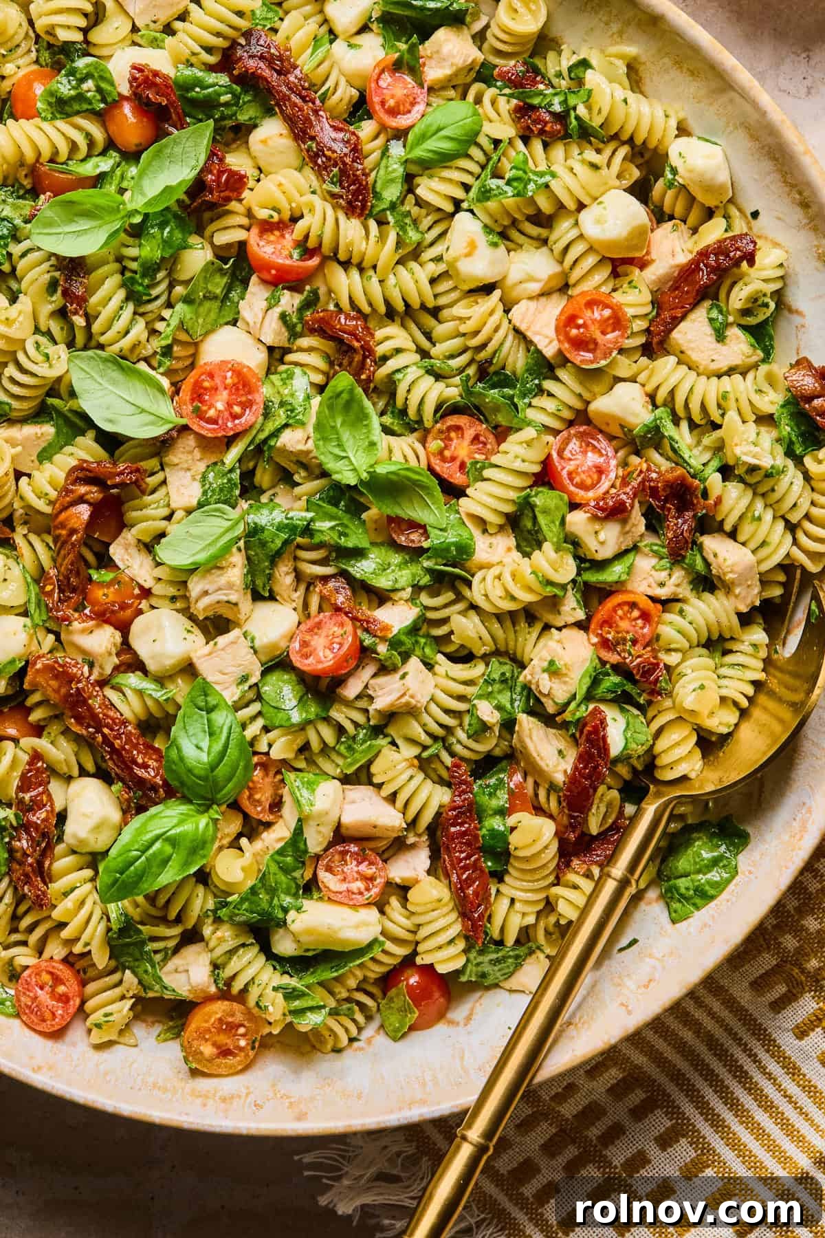 Creamy Pesto Chicken Pasta Salad Recipe for Summer Meals 2 Pesto chicken pasta salad in bowl with serving spoon.