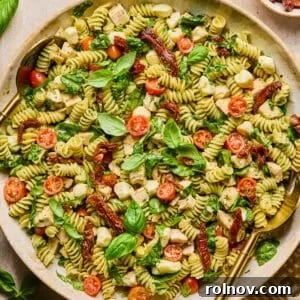 Creamy Pesto Chicken Pasta Salad Recipe for Summer Meals 12 Pesto chicken pasta salad in serving bowl topped with fresh basil with serving spoon.