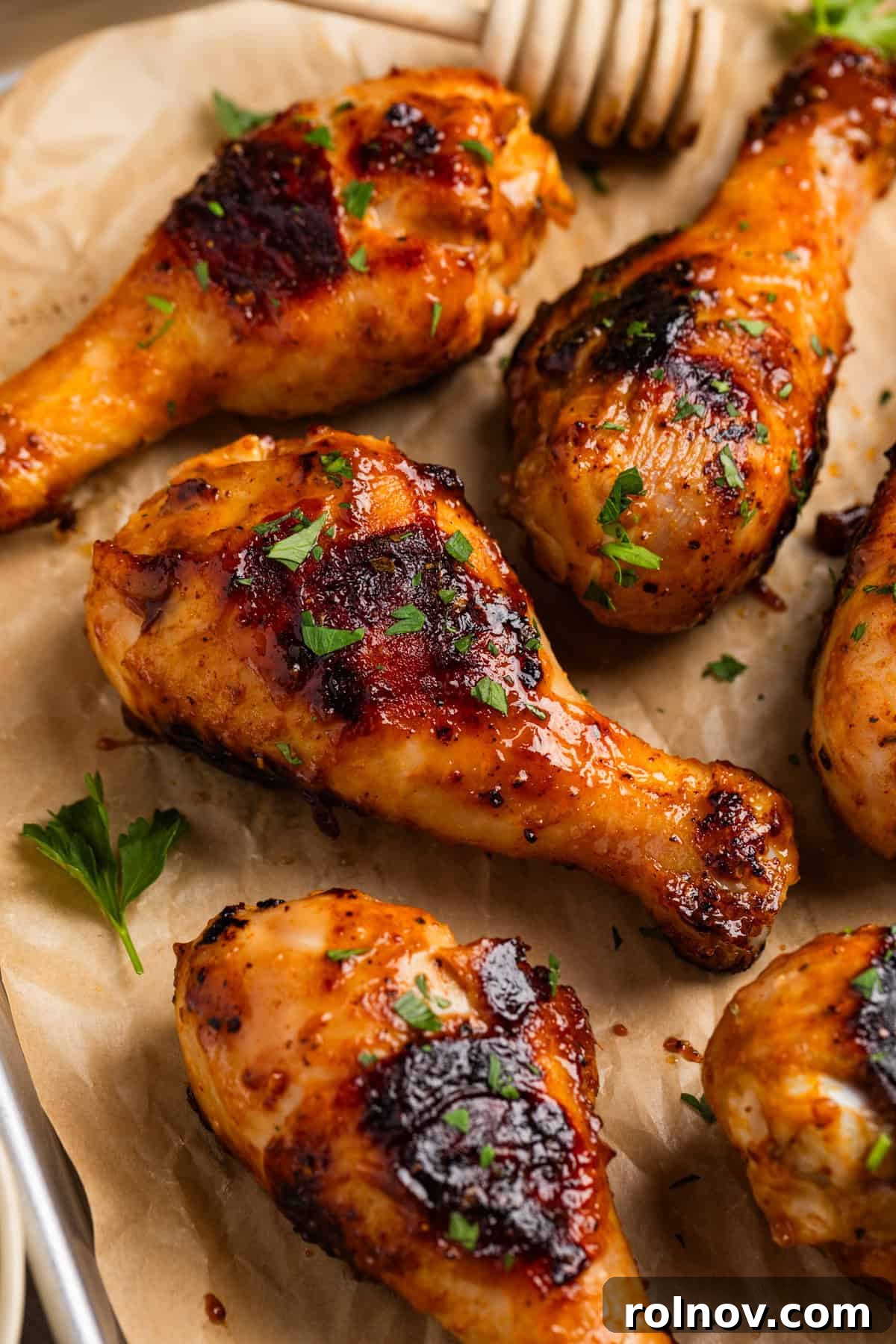 Sticky Honey Mustard Chicken Drumsticks Recipe 2 Honey mustard grilled chicken drumsticks on parchment with chopped parsley.