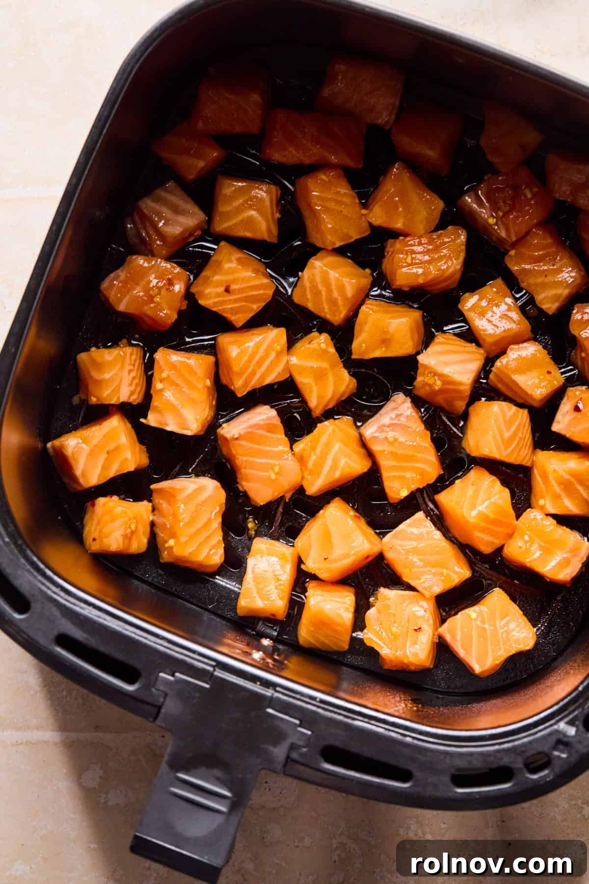 Teriyaki Salmon Rice Bowl with Sesame & Scallions 7 Air fryer with marinaded salmon bites before cooking.