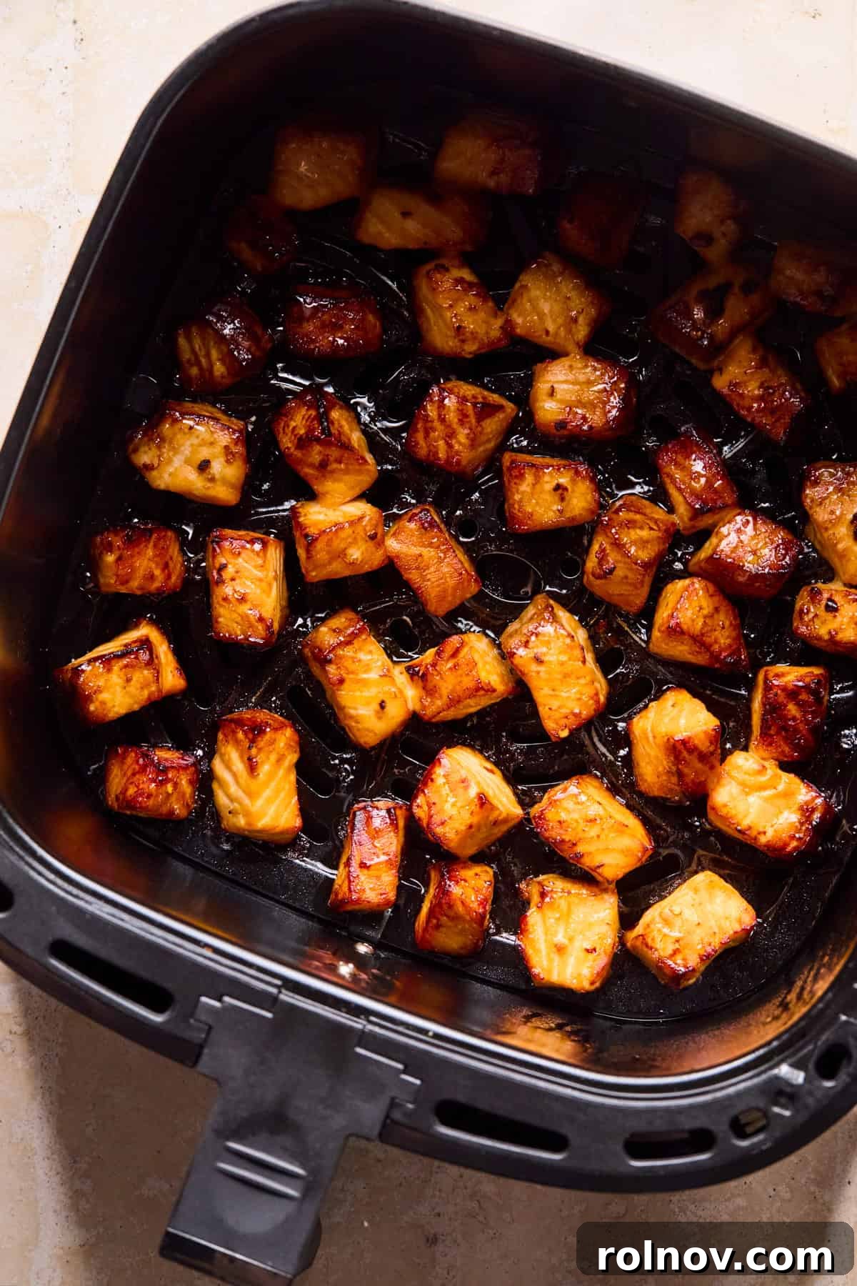 Teriyaki Salmon Rice Bowl with Sesame & Scallions 8 Air fryer with teriyaki salmon bites cooked.