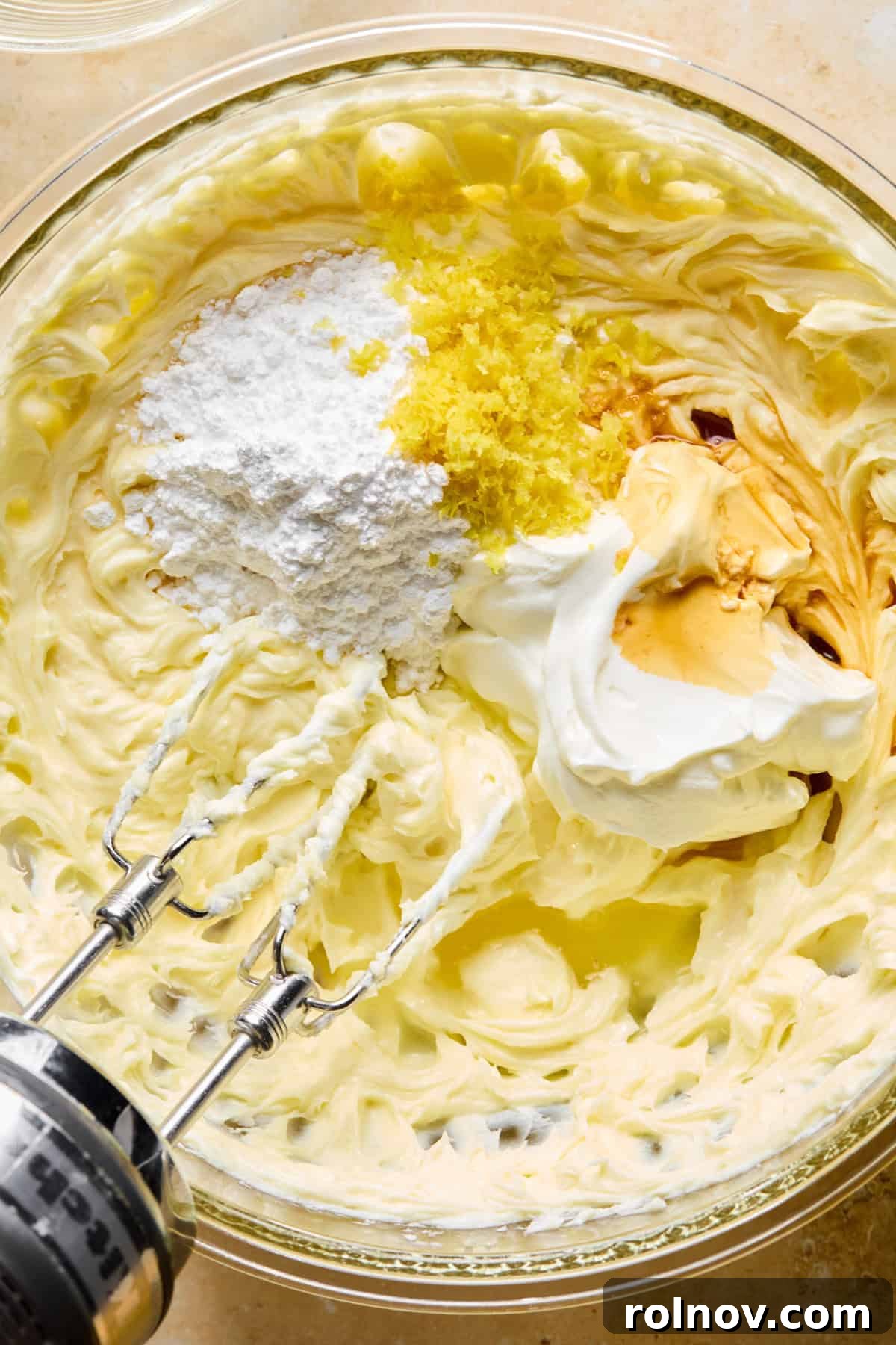 No-Bake Lemon Cheesecake Bars Recipe — Creamy Citrus Dessert 10 Sour cream, lemon zest, powdered sugar and other ingredients in glass mixing bowl with cream cheese mixture.