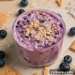 Jar with blueberry cream cheese overnight oatmeal topped with graham crackers.