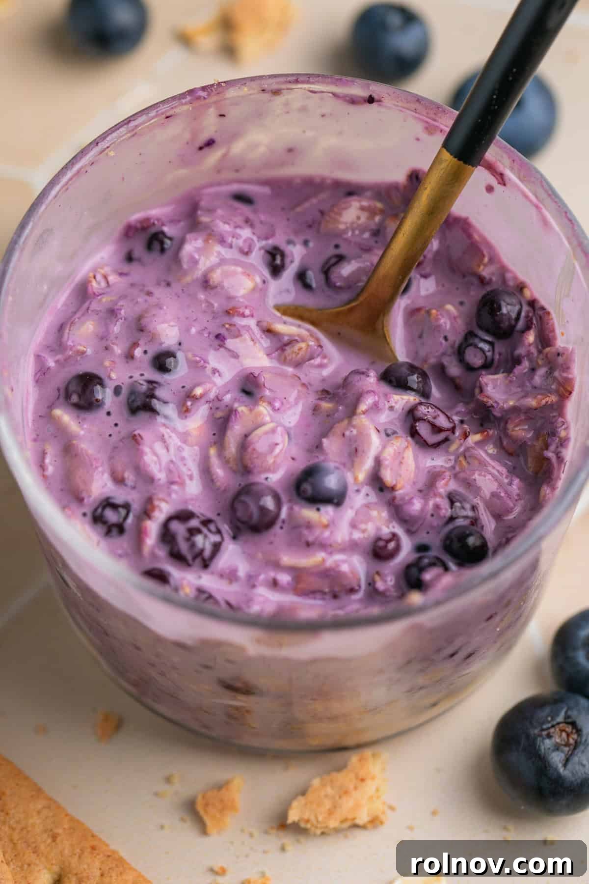 Spoon scooping into cheesecake overnight oatmeal with blueberries.