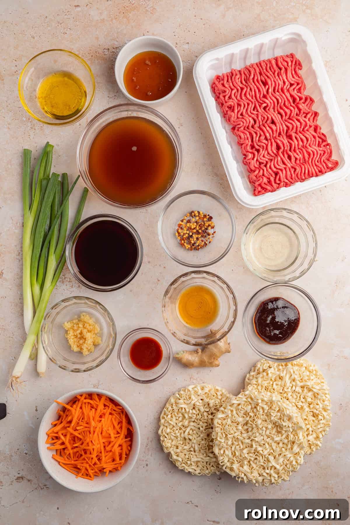 Ground beef, carrots, onions, hoisin sauce and other ingredients arranged on surface for recipe.