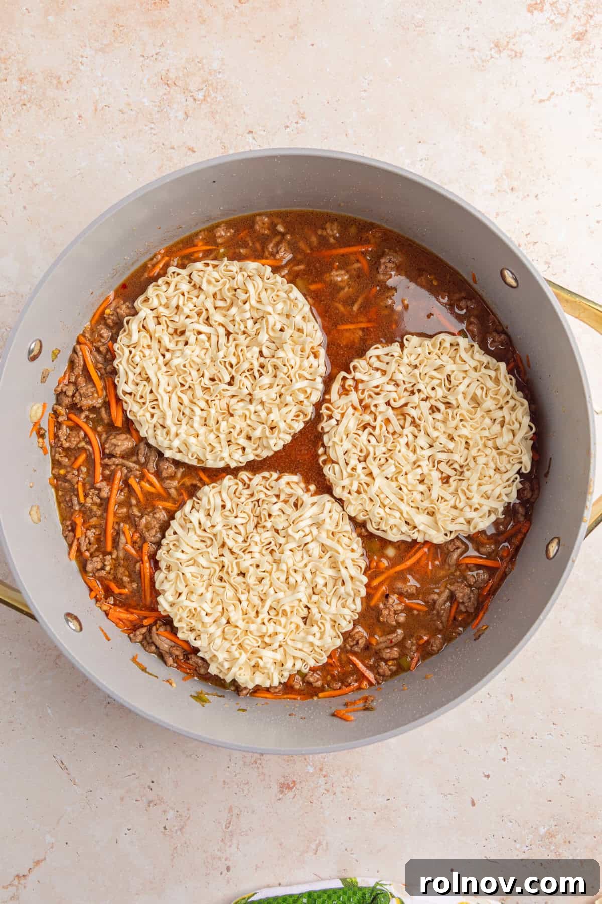 Ramen noodles added to skillet with beef and carrots.