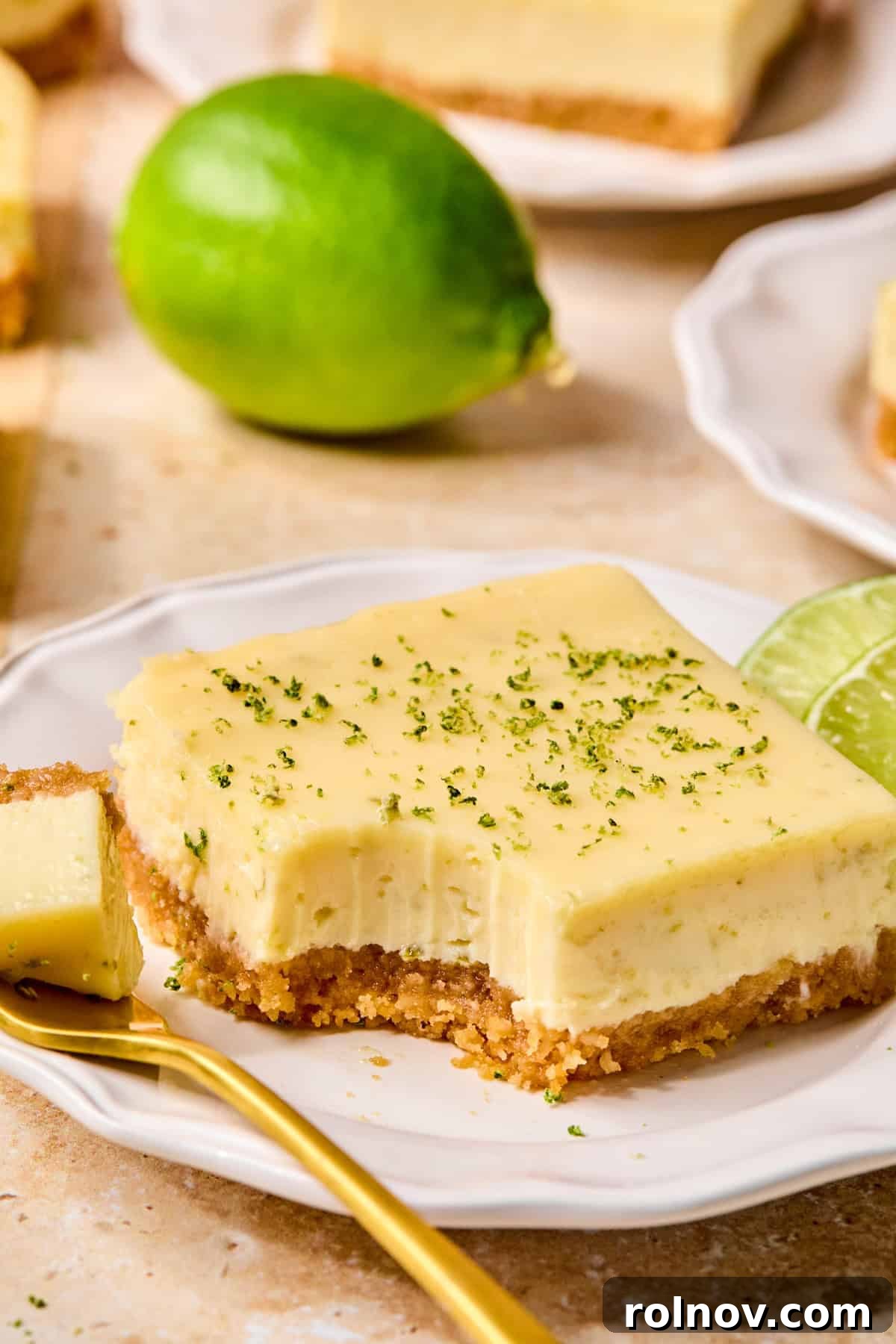 Margarita bar topped with lime zest on white plate with fork.