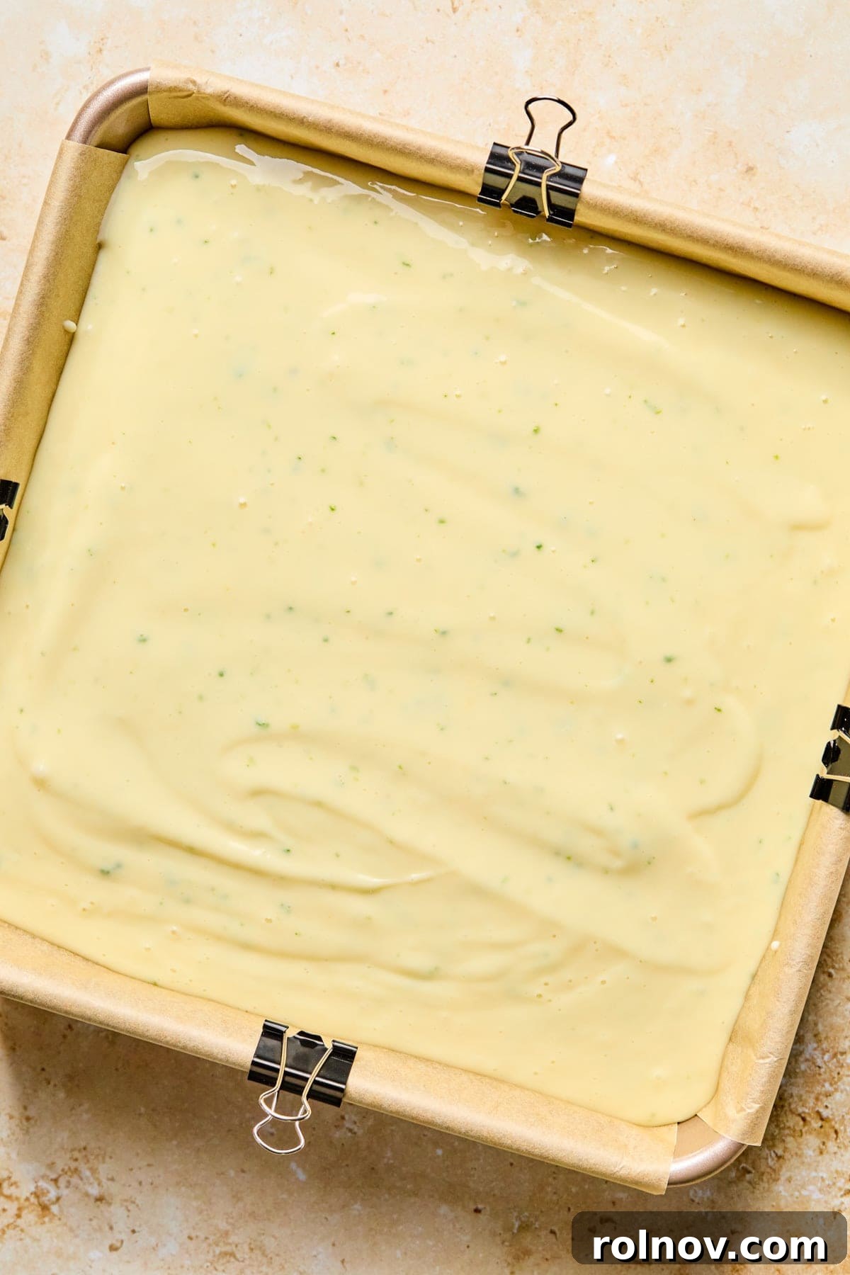 Square baking pan with creamy margarita bar mixture before baking.