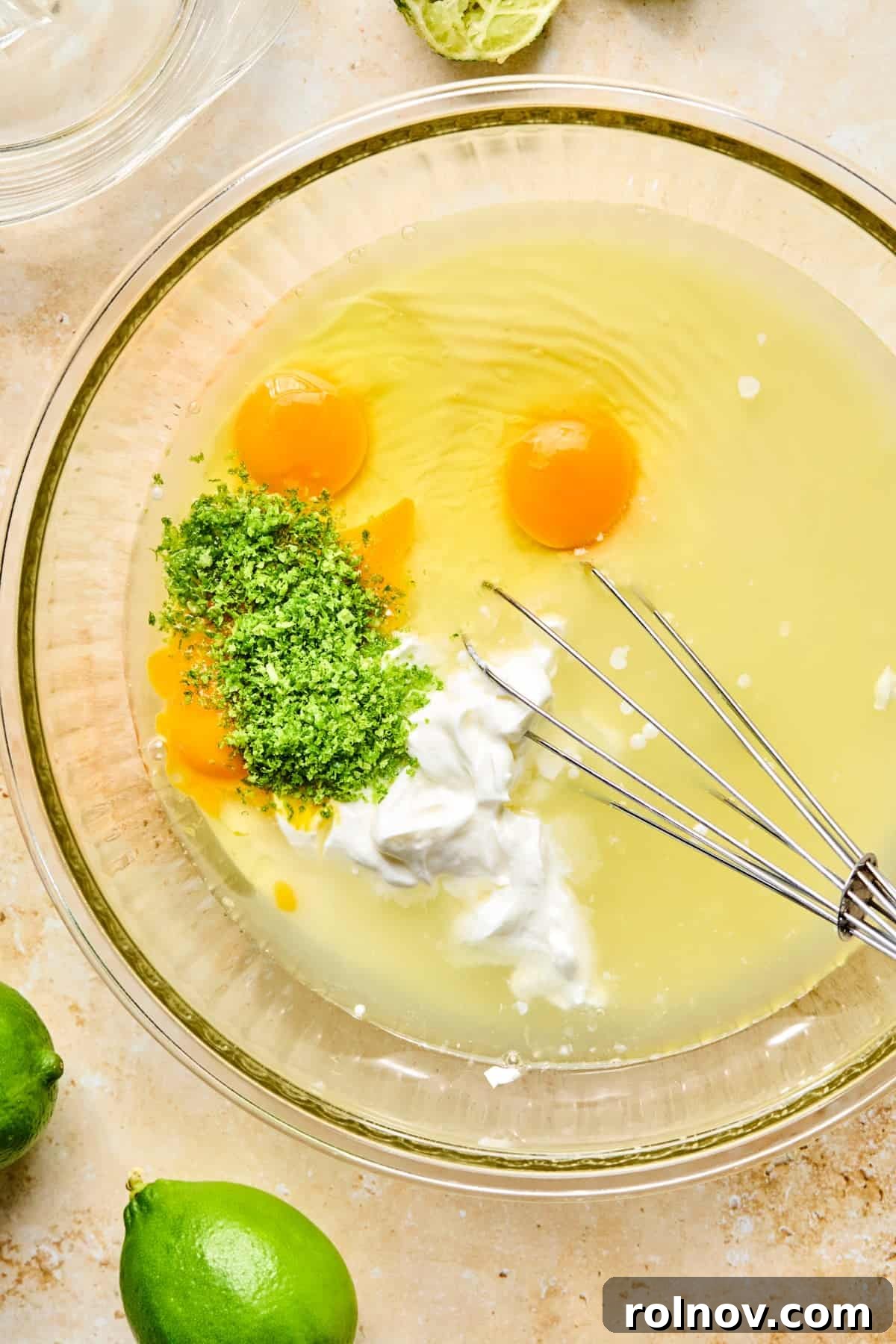 Lime zest and juice, eggs, sour cream and other ingredients in bowl.