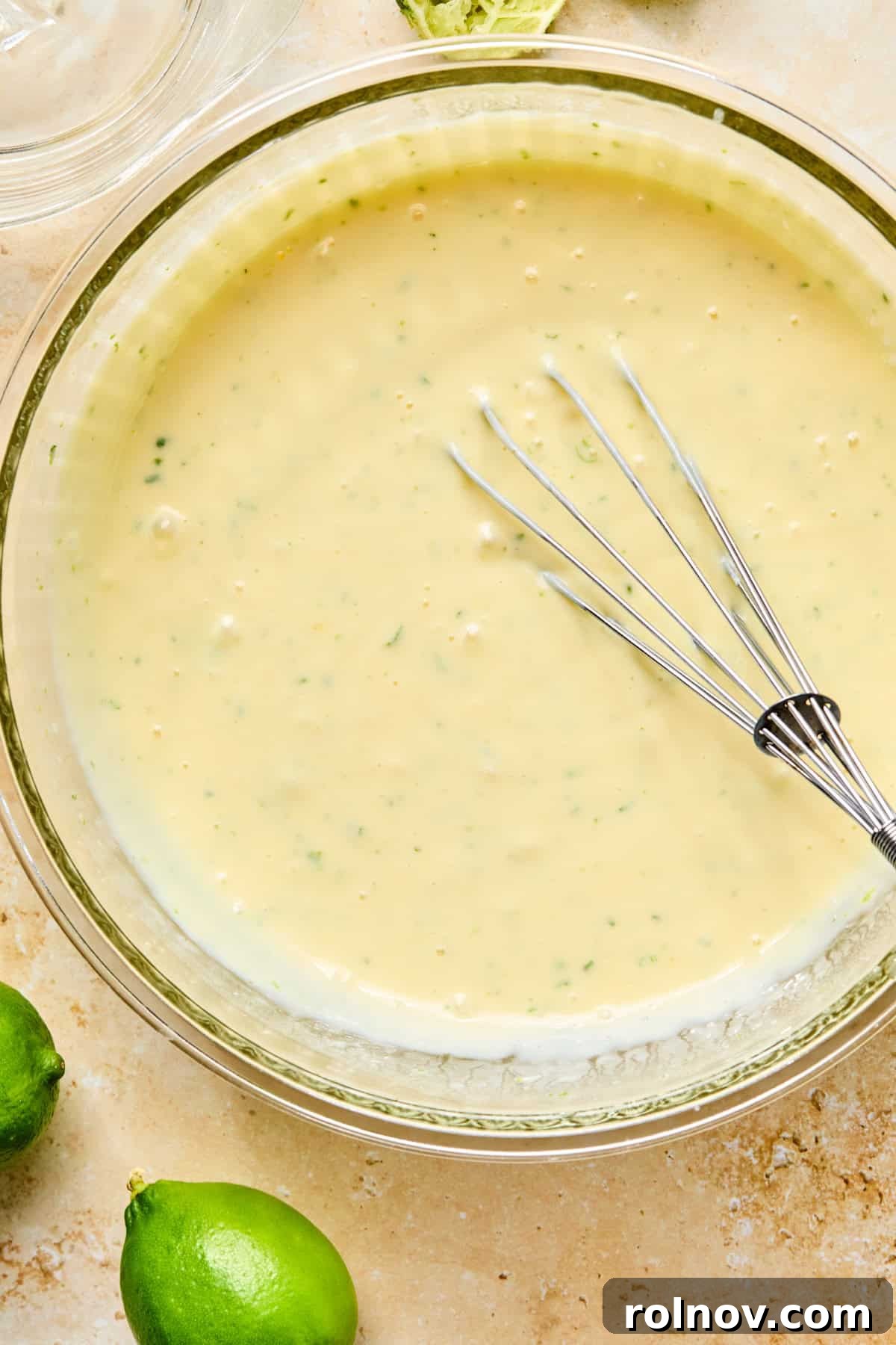 Lime zest, lime juice, eggs, sweetened condensed milk and other ingredients whisked in bowl.