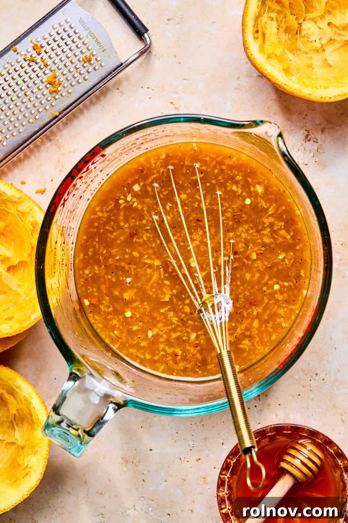 Whisked orange chicken sauce mixture in glass measuring cup.