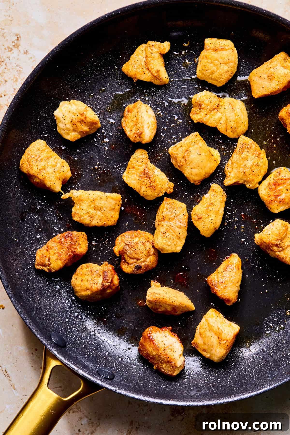Browned chicken bites in skillet.