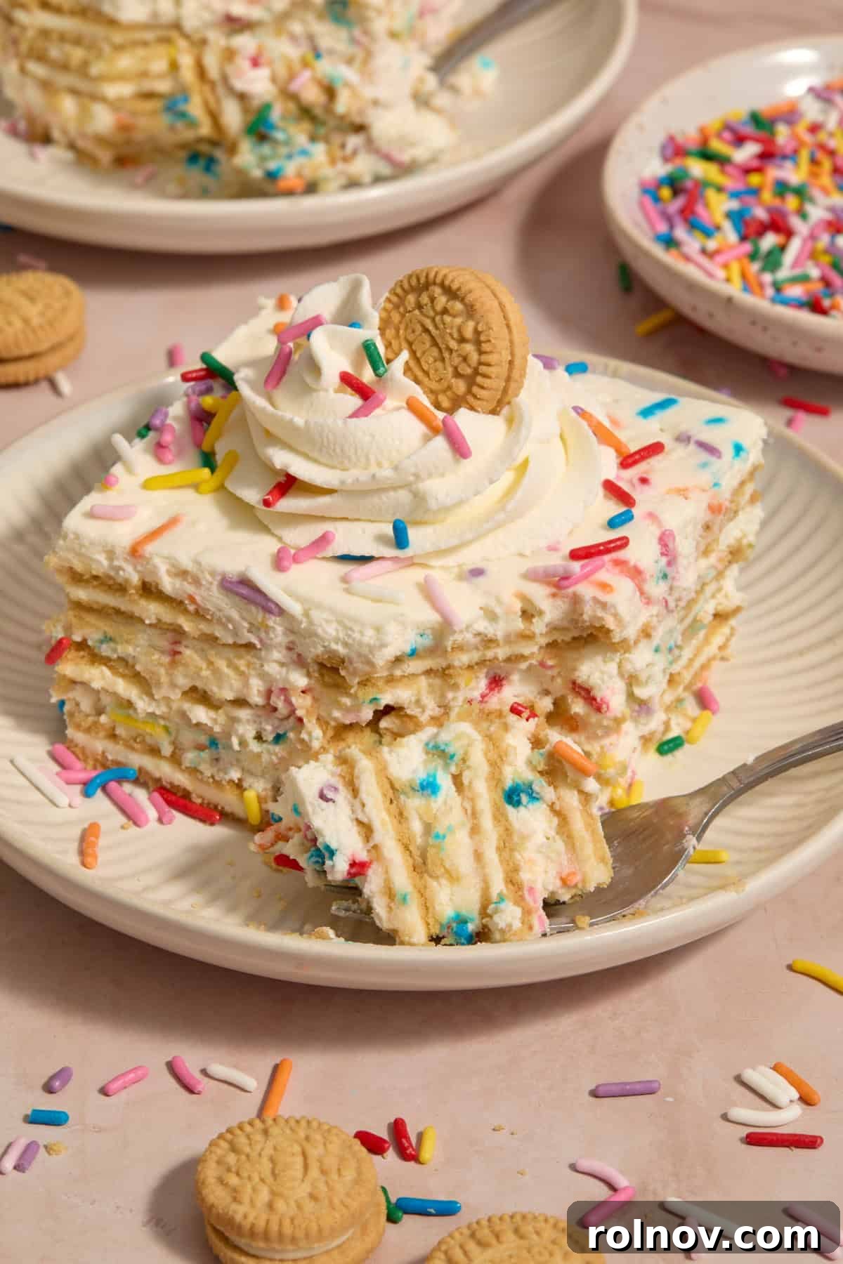 Slice of funfetti layered cake with forkful propped beside the plate.