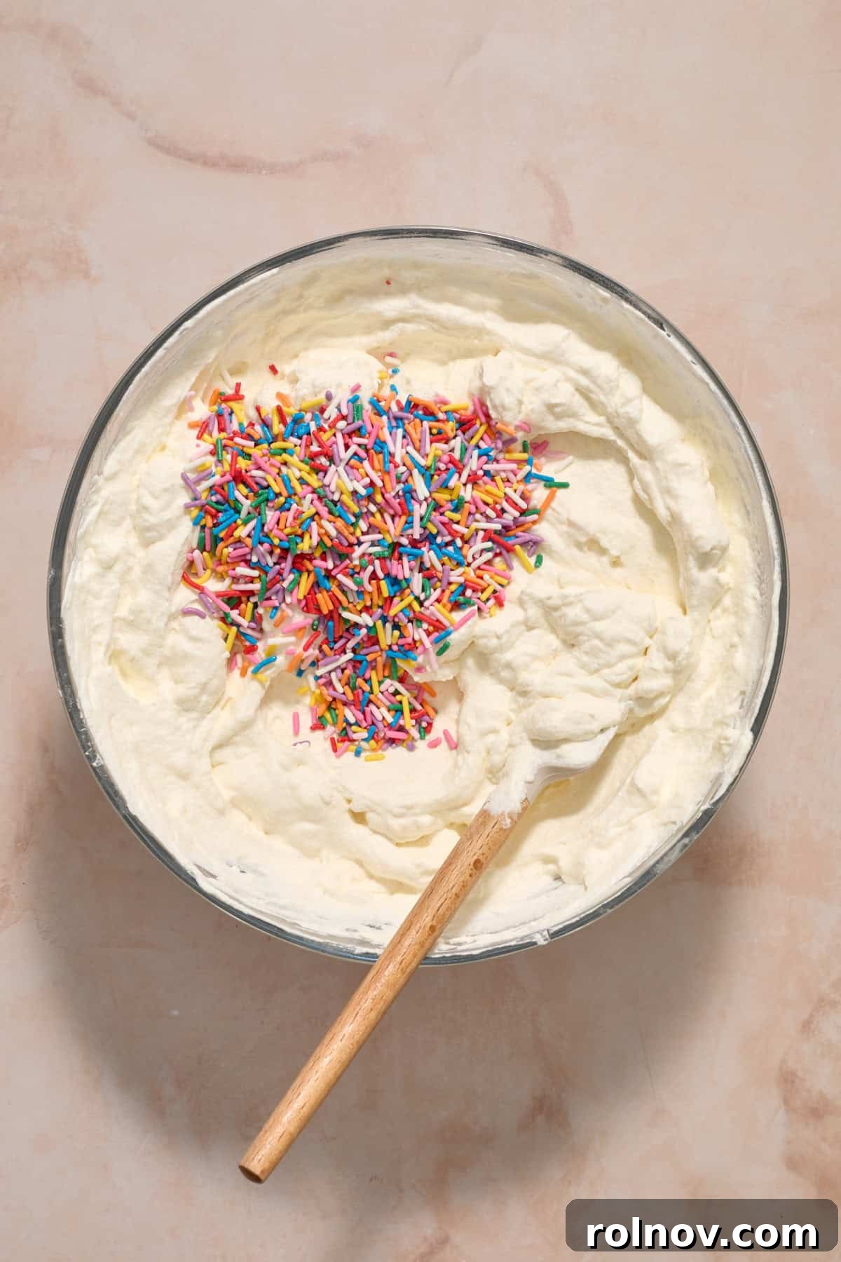 Sprinkles added to cream cheese and whipped cream mixture in bowl.