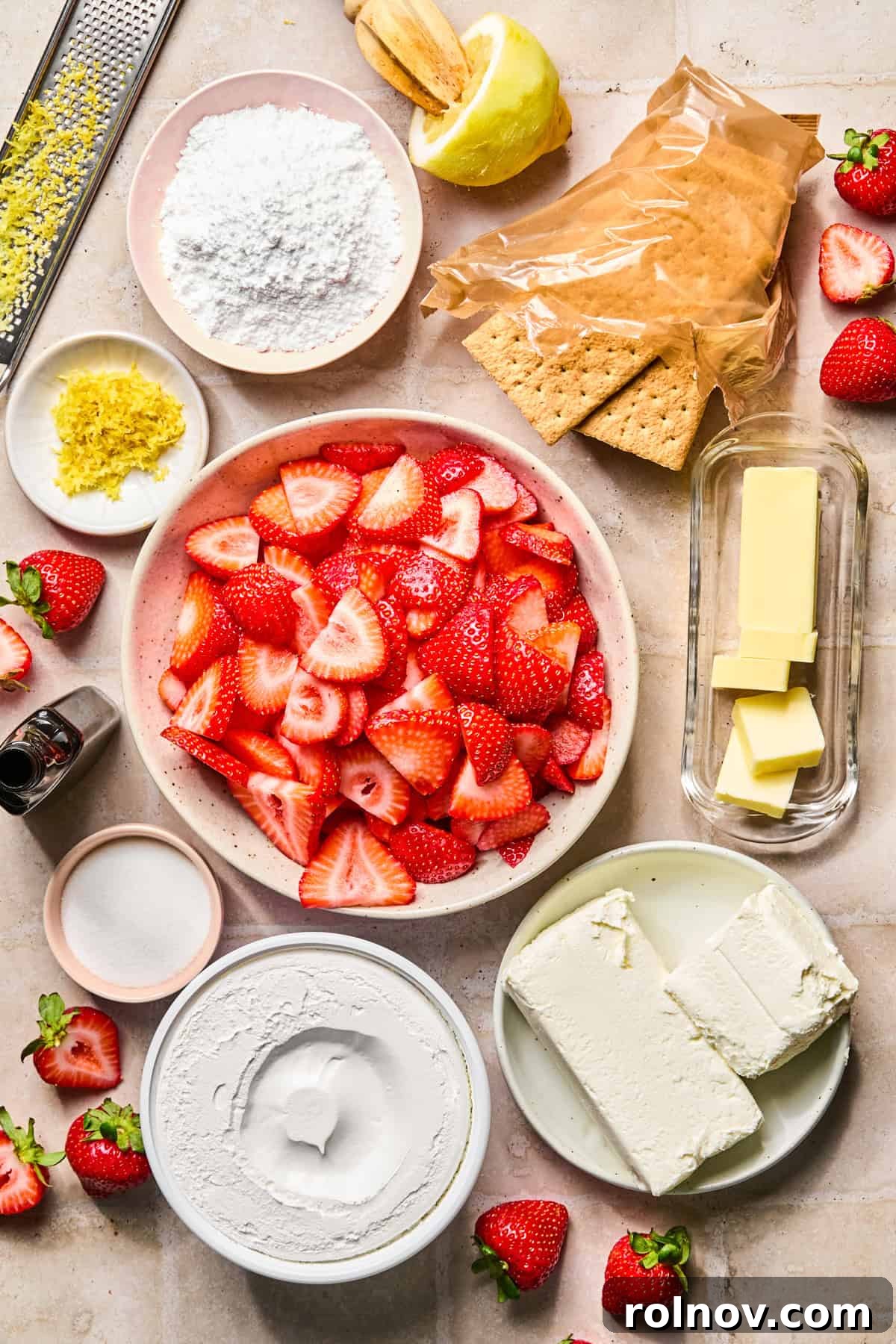 Roasted Strawberry Mini Cheesecake Cups Recipe 4 Sliced strawberries, butter, lemons, graham crackers, and other ingredients on surface.