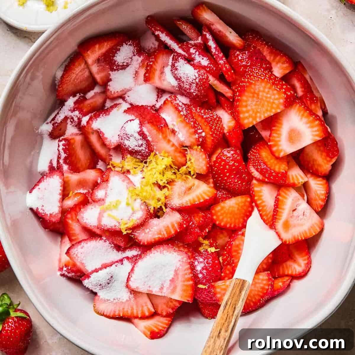 Roasted Strawberry Mini Cheesecake Cups Recipe 5 Sliced strawberries in bowl with sugar and lemon zest.